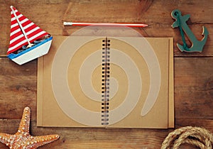 Top view image of open blank notebook, wooden sailboat, nautical rope. travel and adventure concept. retro filtered image