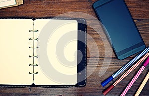 Top view image of open blank paper leather notebook with pen on wooden background.