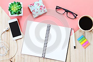 Top view image of open notebook with blank pages, accessories and coffee cup on wooden background, ready for adding or mock up