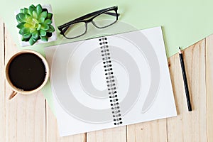 top view image of open notebook with blank pages and coffee cup on wooden background, ready for adding or mock up