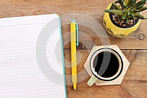 top view image of open notebook with blank pages and cup of coffee over wooden desk. ready for adding text or mockup