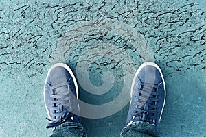 Top view image of person with sneakers on asphalt with cracks. Concept of confusion and doubt