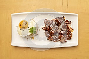 Top view image of Philippine popular dish of tocilog with fried egg, poppy seeds on the yolk, bowl of white rice