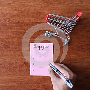 Top view image of shopping trolley and paper with text Shopping List