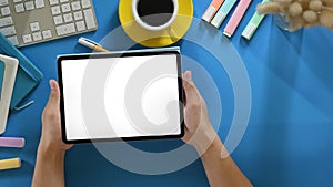 Top view image of smart man`s hands holding a cropped black computer tablet with white blank screen .