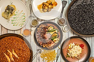 Top view image of Spanish dishes and paellas. Seafood paella, black rice paella with squid, cod al pil pil,