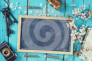 Top view image of spring white cherry blossoms tree, blackboard, old camera on blue wooden table