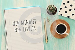 Top view image of table with open notebook and the text new mindset new results. success and personal development concept