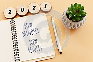 Top view image of table with open notebook and the text new mindset new results. success and personal development concept