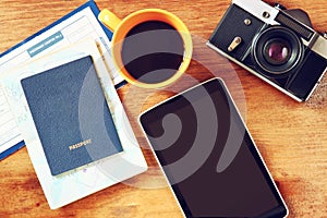 Top view image of tablet with empty screen, old camera passport and flight boarding pass