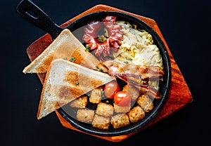 Top view image of western brunch menu on pan and wooden plate. American style breakfast served with toast, hash brown, sausages,