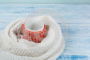 Top view image of white cozy knitted sweater with to cup of coffee on a wooden table.