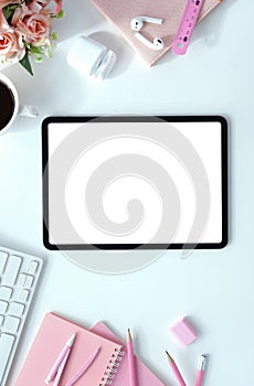 The top view image of white workspace is surrounding by a white blank screen tablet