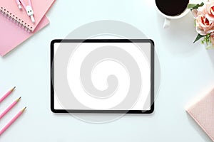 The top view image of white workspace is surrounding by a white blank screen tablet