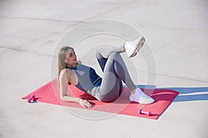 Top view image of young sportive woman, keeping body in tune, doing stretching exercises on warm sunny day outdoors