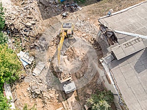 Top view of industrial machinery working at demolition site in garbage and ruins