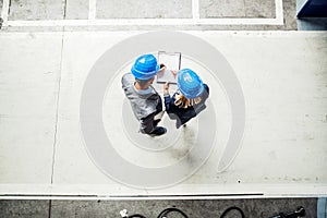 A top view of an industrial man and woman engineer with clipboard in a factory.