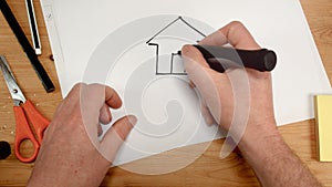 Top view, an interior architect`s hand draws a house inside a heart on a sheet of paper, ideal footage for topics such