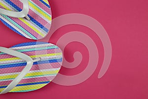 Top view on isolated colorful striped pair flip flops on pink background with copy space