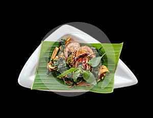 Top view of isolated spicy spaghetti seafood with crispy basil on banana leaf. With clipping path