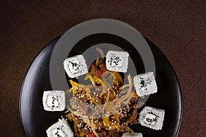 top view Japanese cuisine, rice rolls with sesame seeds and soy sauce on a black plate