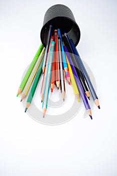Top view of a jar full of different colored pencil crayons fallen on a white background