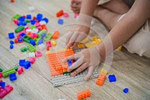 Top view. Joyful Asian girl happy and smiling playing colorful Lego toys, sitting on the living room floor, creatively playing