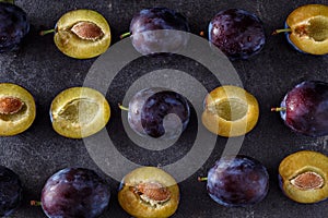 Top view on juicy plums, whole and slices on dark background