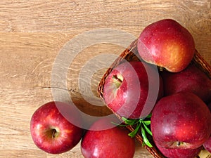Top view of juicy red organic apples in a basket on oak tree wood background. Autumn Fall season orchard harvest production.