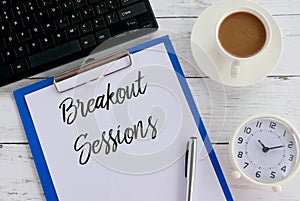 Top view of keyboard,coffee,clock,pen,clipboard and paper written with Breakout Sessions photo