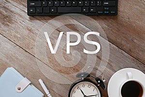 Top view of keyboard,notebook,pen,clock, and a cup of coffee on wooden background written with VPS