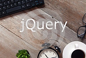 Top view of Keyboard,sunglasses, a cup of coffee,clock and plant on wooden background written with jQuery