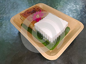 top view Khanom Mor Kaeng and Khanom Chan Placed on pink flower and on green leaf banana, paper plate on a grass table background photo