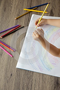 Top view of kid drawing rainbow with color