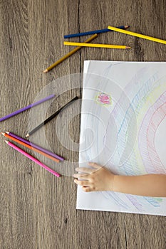 Top view of kid drawing rainbow with color