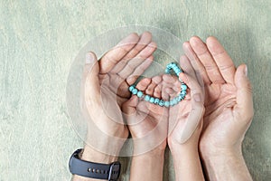 top view on kid hands holding rosary beads in father& x27;s hands. Ramadan Kareem background. Muslim man and child holds a