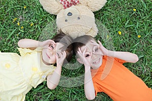 Top view of kids lying on the grass at park having fun. Little girl and boy relax with smiling