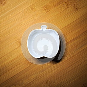 Top view of kitchenware, single white ceramic bowl of apple shape design on wood dining table background