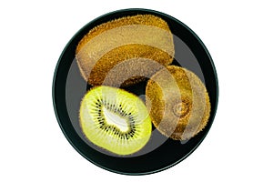 Top view of kiwi fruit whole and a half in black ceramic bowl on white background