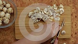 Top view of a knife cutting champignons into small pieces