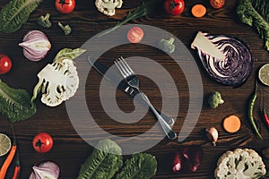 Top view of knife and fork with different vegetables on brown