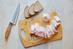 Top view of knife and slices of bread near cutting board, having lard an garlic to taste, Ukrainian traditional appetizer, food