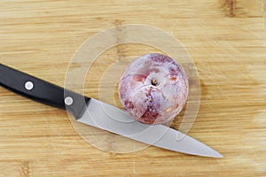 Top View of a Knife on a Wood Chopping Board with a Plum