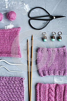 Top view: knitting accessories samples of knitted products lie on a gray concrete background. Place for inscription