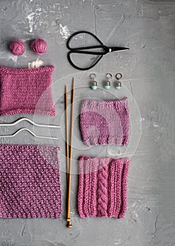 Top view: knitting accessories samples of knitted products lie on a gray concrete background. Place for inscription