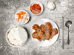 Top view Korean Spicy deep-fired chicken with steamed rice and side dish on the gray concrete table