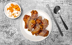 Top view Korean spicy deep-fried chicken topped white sesame with pickled  carrot and pickled radish side dishes on the gray concr