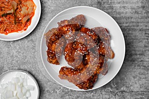 Top view Korean spicy fried chicken with side dishes on gray concrete table.