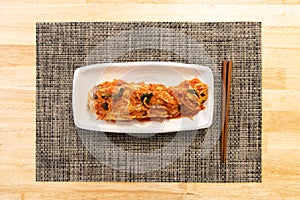 Top view of Korean traditional radish food, Kimchi, on a white plate with chopstick