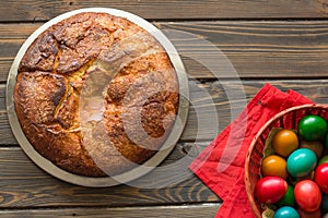 Top view of a Kozunak Traditional Easter homemade sweet bulgarian bread and colored eggs in a red wicker basket